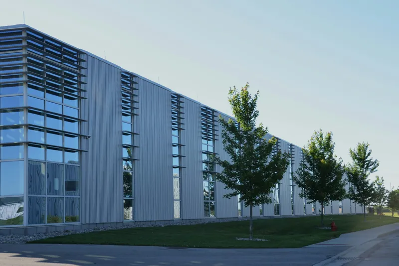 A long low rise office building with tall windows and young trees