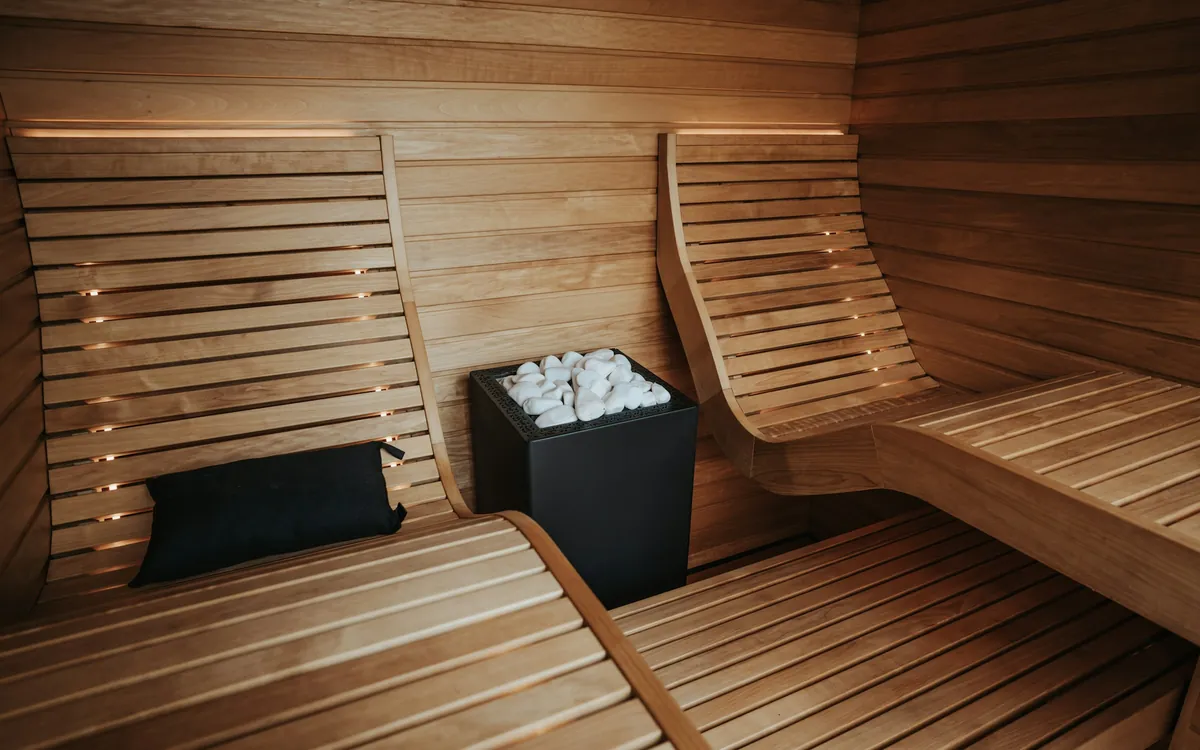 A timber sauna with curved benches and a stone heater